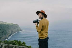 sonriente hombre con un cámara a el costa en sao miguel isla, azores, Portugal foto