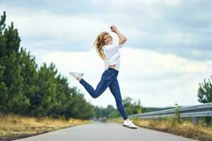 Cheerful woman jumping on rural road photo