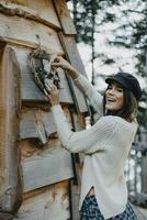 Happy young woman decorating wooden house with Christmas decoration photo