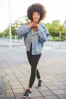 retrato de contento joven mujer con afro peinado en el ciudad foto