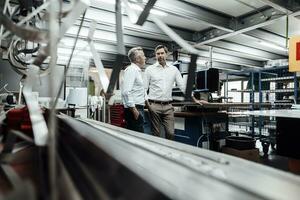 Business people planning while standing at industry photo