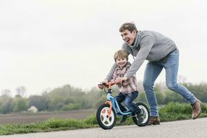 Father teaching his son how to ride a bicycle, outdoors photo