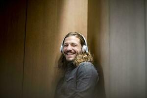 retrato de riendo hombre escuchando música con auriculares foto