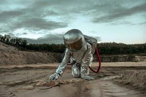 Spaceman exploring nameless planet, searching the soil photo