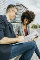 Two happy colleagues working together outside office building photo