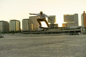 joven hombre haciendo un patineta truco en el ciudad a puesta de sol foto