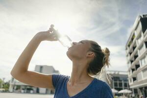 Netherlands, Maastricht, young woman drinking from bottle in the city photo