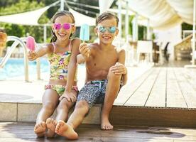 Portrait of happy little girl and boy wearing mirrored sunglasses showing their popsicles photo