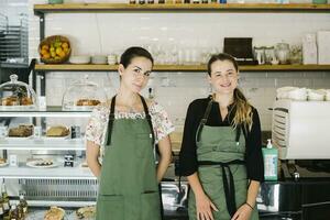 Smiling women standing by counter at coffee shop photo