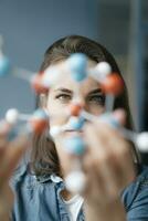 Female scientist studying molecule model, looking for solutions photo