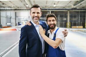 Portrait of happy businessman and worker in a factory photo