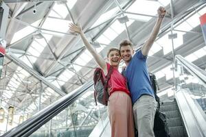 contento Pareja aplausos en escalera mecánica a el aeropuerto foto