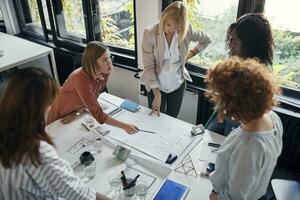 Businesswomen having a meeting in office with blueprints on table photo