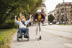 Senior man in wheelchair having fun with his adult grandchildren outdoors photo