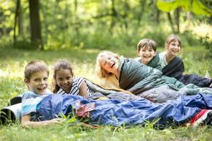 School children camping in forest, lying in sleeping bags photo