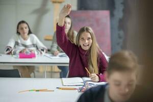 Happy teenage girl raising hand in class photo