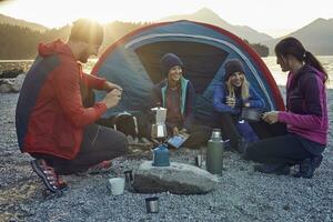 Group of hikers camping at lakeshore at sunset photo