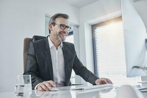 Happy businessman working at desk in office photo