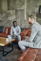 Two happy businessmen having a coffee break in hotel lobby photo