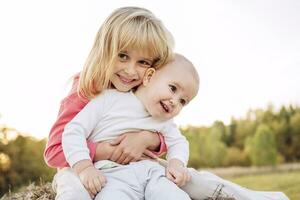 Sister embracing female toddler against clear sky photo