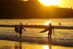 Surfers at sunset on the beach, Bali, Indonesia photo