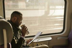 Stylish businessman with reusable cup and documents in a train photo