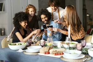 Friends sitting at dining table, looking at photographs photo