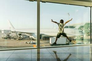 España, Barcelona aeropuerto, chico en salida área, saltando en frente de vaso cristal foto