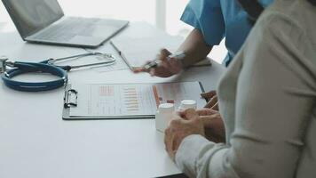 Doctor and patient sitting and talking at medical examination at hospital office, close-up. Therapist filling up medication history records. Medicine and healthcare concept. video