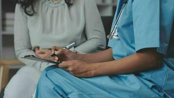 médecin et patient séance et parlant à médical examen à hôpital bureau, fermer. thérapeute remplissage en haut des médicaments histoire enregistrements. médicament et soins de santé concept. video