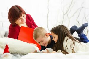 children and mother are lying on the bed photo