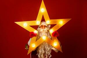 Funny santa claus with big star in Christmas on red background photo