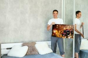 man holds photo canvas at home