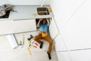 Handsome professional plumber doing sink reparation. Contractor. photo