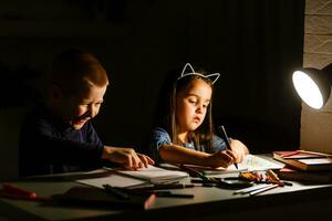 Little American girl boy doing homework in evening at home photo
