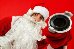 Christmas man in santa clothes with fire Hose standing against isolated red background photo