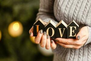 mujer sostiene letras amor cerca Navidad árbol con juguetes foto
