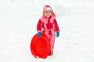 Little girl riding on snow slides in winter time photo