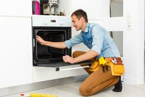 joven reparador instalando inducción Horno en cocina foto