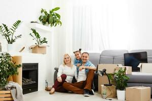 Happy family sitting on wooden floor. Father, mother and child having fun together. Moving house day, new home and design interior concept photo