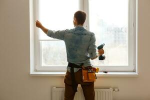 Man worker mounting window on balcony. photo