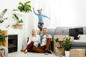 Happy family sitting on wooden floor. Father, mother and child having fun together. Moving house day, new home and design interior concept photo