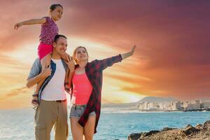 contento joven familia tener divertido en playa correr y saltar a puesta de sol foto