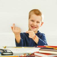 Smart, cheerful, happy, small, boy, schoolboy at the table solves problems and lessons photo