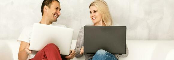 Young couple relaxing on sofa with digital two laptop. photo