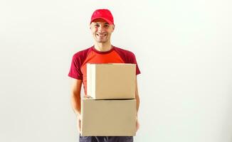 Photo of happy man from delivery service in red t-shirt and cap giving food order and holding two boxes isolated over white background