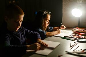 Little girl and boy doing homework in evening at home photo