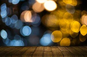 Old weathered wooden board or rustic table top with a sparkling bokeh of golden party lights in the background photo