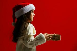 Happy child holding Christmas presents on a red background. Christmas time. Children's birthday. photo