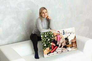 Young girl holds photo canvas at home on the couch